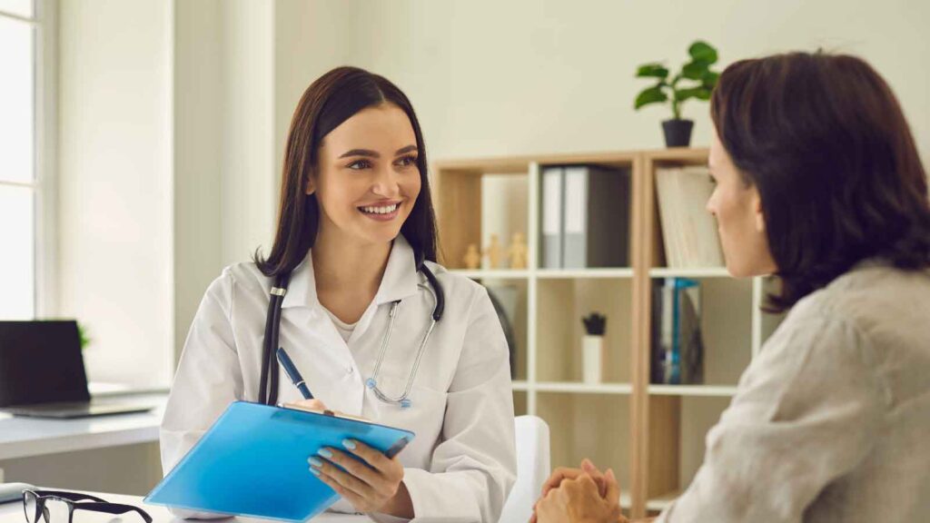 Smiling doctor talking to a patient while holding a clipboard.